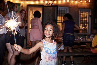 Young girl holding a sparkler at an outdoor celebration