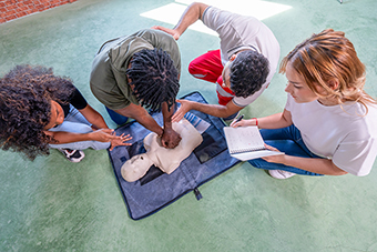 Teens practicing CPR on a dummy with an instructor