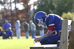 High school football player sitting on bench with his head down